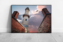 Laad de afbeelding in galerijviewer, Weathered Lighthouse Under Dramatic Fiery Sky With A Seagull Passing Through Rostock Wall Art Print on Paper Framed Picture print
